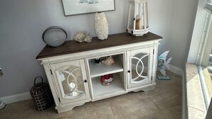 A white cabinet with glass doors, a framed picture above it, and a decorative item on top. - Key largo home (Key Largo)