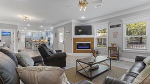 A modern living room with leather sofas, a fireplace, and a television. - Beautiful new home just mins to the beach, aquarium, BUC-EES, and Downtown! (Gulfport)