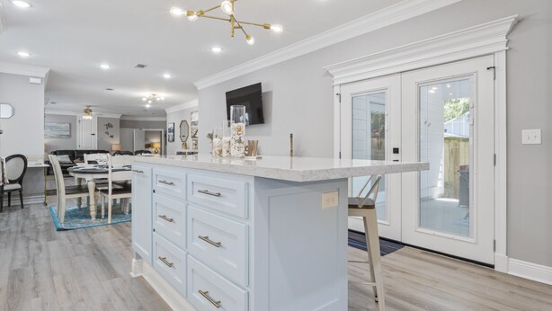 A modern kitchen with a central island, white cabinetry, and a chandelier. - Beautiful new home just mins to the beach, aquarium, BUC-EES, and Downtown! (Gulfport)