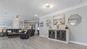 A spacious living room with a leather sofa, a recliner, and a console table with decorative items. - Beautiful new home just mins to the beach, aquarium, BUC-EES, and Downtown! (Gulfport)