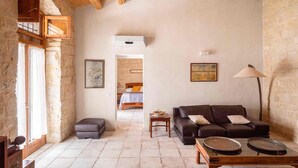 A spacious living room with a stone wall, a wooden ceiling, a sofa, a coffee table, and a lamp. - Lovely Sicilian-style villa with pool and sea view, 3 Km from the beach  (Scicli)