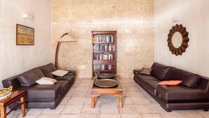 A cozy living room with two leather sofas, a wooden coffee table, a bookshelf, and a stone wall. - Lovely Sicilian-style villa with pool and sea view, 3 Km from the beach  (Scicli)