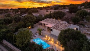 A villa with a swimming pool, surrounded by trees and hills, during sunset. - Lovely Sicilian-style villa with pool and sea view, 3 Km from the beach  (Scicli)