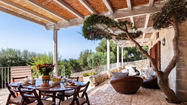 A covered outdoor dining area with a stone floor, wooden furniture, and a view of the landscape. - Lovely Sicilian-style villa with pool and sea view, 3 Km from the beach  (Scicli)