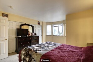 Cozy retreat with a large bed, dresser, and TV, offering a comfortable space to unwind.