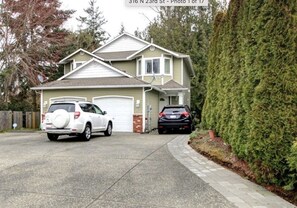 Two-story house with a garage, surrounded by a well-maintained hedge and fence.