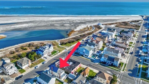 Vue aérienne d’une zone résidentielle côtière, avec des maisons, une route et une plage.