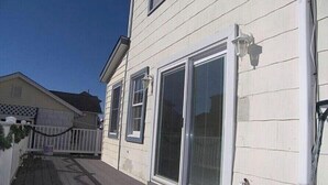 Une maison dotée d’un porche abrité, de grandes portes-fenêtres coulissantes et d’une façade blanche.
