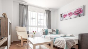 A modern, well-lit room with a bed, a chair, a table, and a painting on the wall. - High quality apartment 3 bedrooms, 2 bathrooms & patio/ wifi. La Algaba (Algaba)
