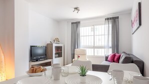 A modern living room with a dining area, a TV, and a sofa with cushions. - High quality apartment 3 bedrooms, 2 bathrooms & patio/ wifi. La Algaba (Algaba)