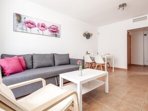 A modern living room with a grey sofa, a white coffee table, and a dining area with a white table and chairs. - High quality apartment 3 bedrooms, 2 bathrooms & patio/ wifi. La Algaba (Algaba)