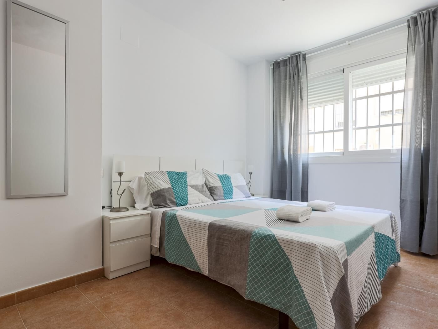 Une chambre à coucher avec un lit, une table de chevet et une fenêtre avec des rideaux.