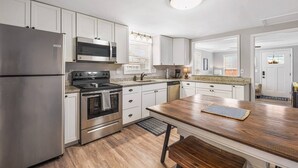 Una cocina moderna con electrodomésticos de acero inoxidable, armarios blancos y una isla de madera.