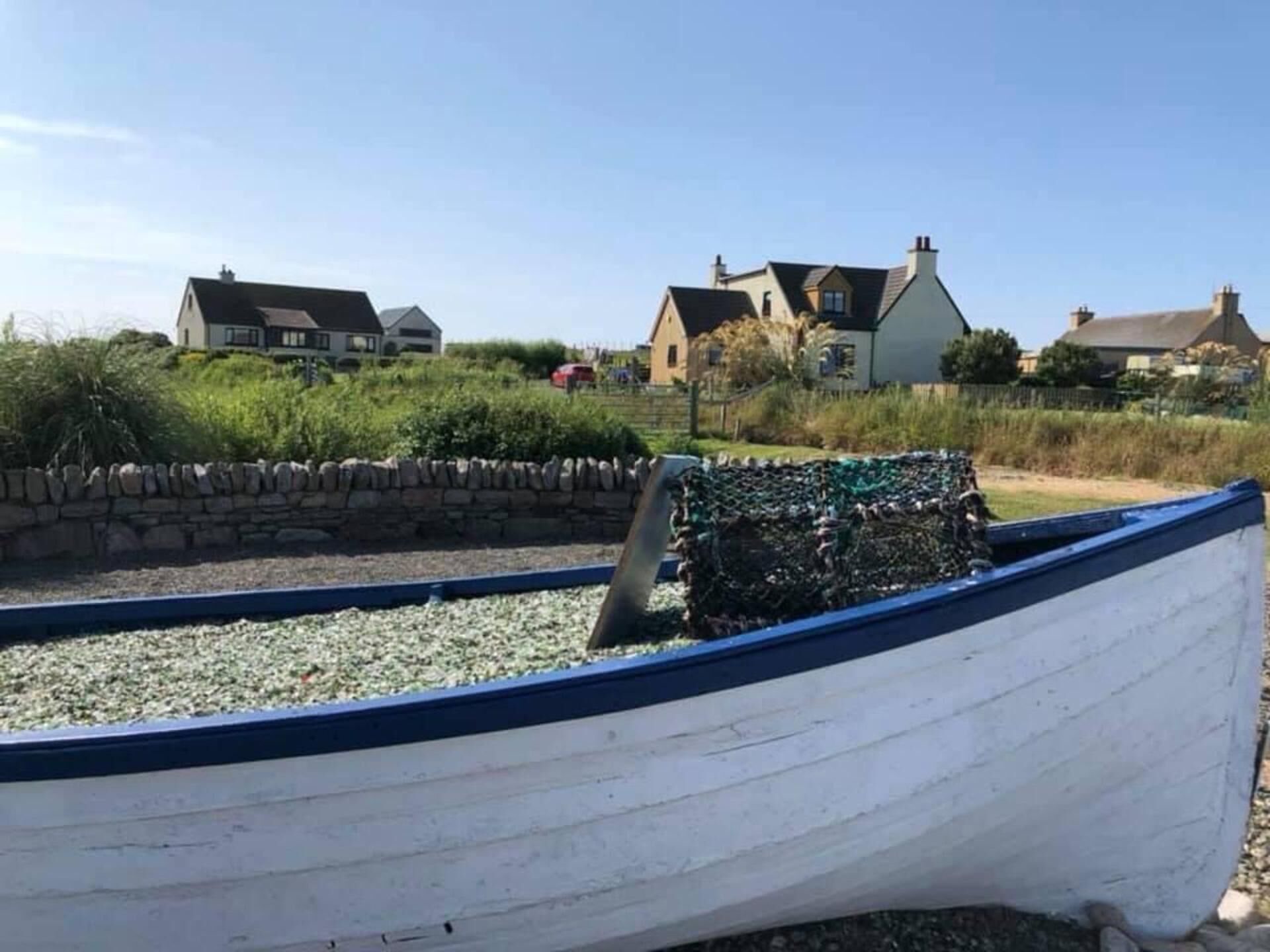 A boat on a gravel surface with houses in the background.