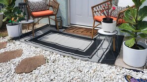 A patio area with wicker chairs, a white door with a wreath, and potted plants. - Modern Bohemian Studio - in Golf neighborhood - Disney 15 min (Davenport)