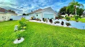 A residential house with a garage, surrounded by a well-maintained lawn and various plants. - Modern Bohemian Studio - in Golf neighborhood - Disney 15 min (Davenport)