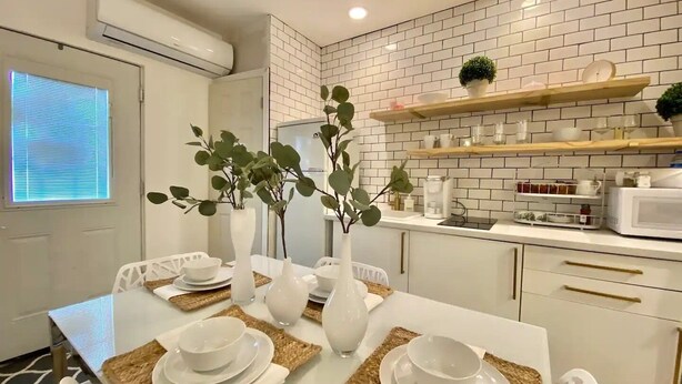 A modern kitchen with white cabinets, a microwave, and a shelf with kitchenware. - Modern Bohemian Studio - in Golf neighborhood - Disney 15 min (Davenport)