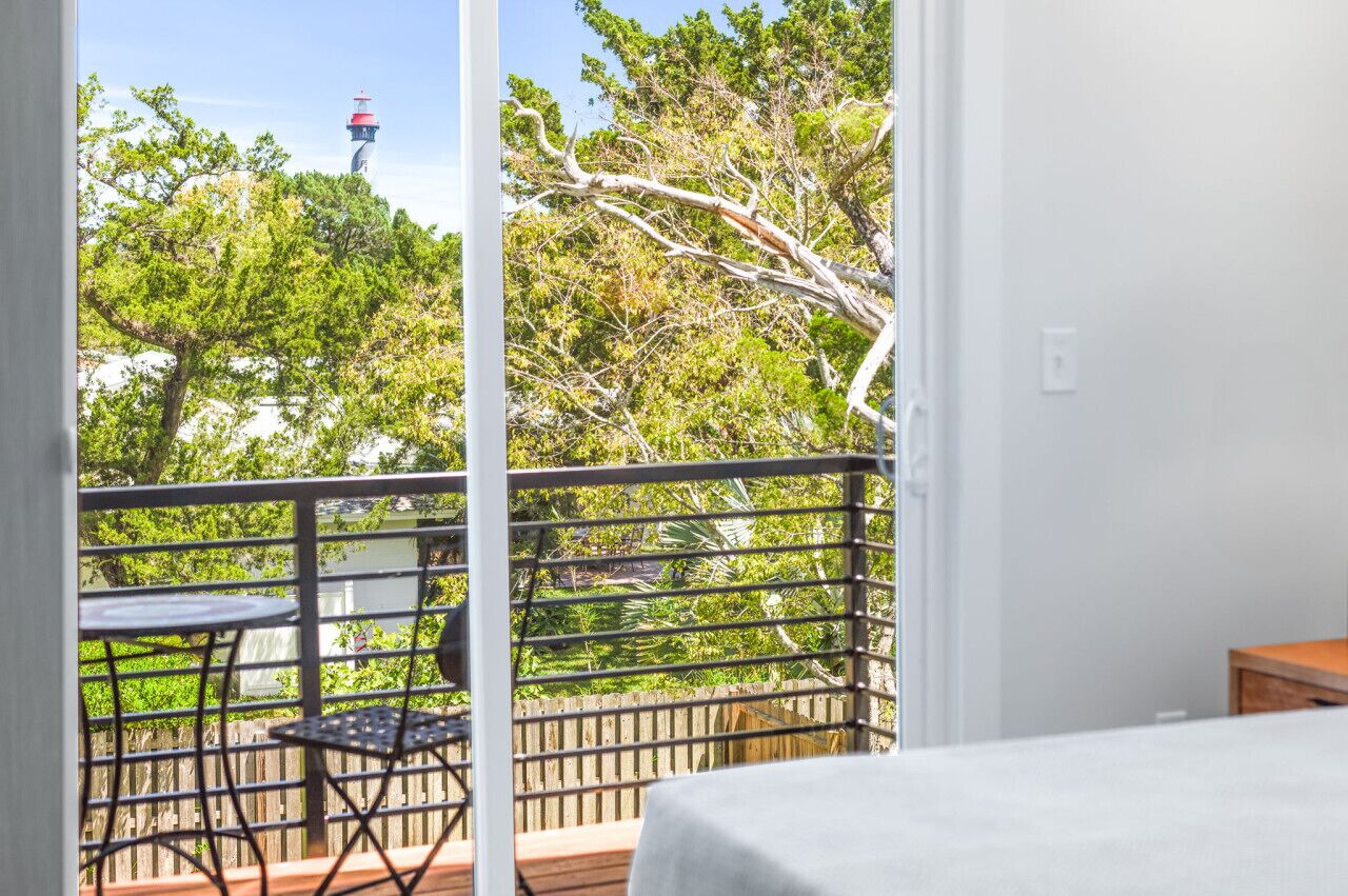 A balcony with a view of trees and a lighthouse.