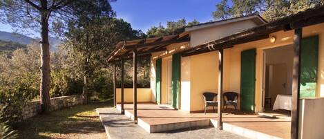 A covered outdoor area with a stone bench, a table, and chairs.