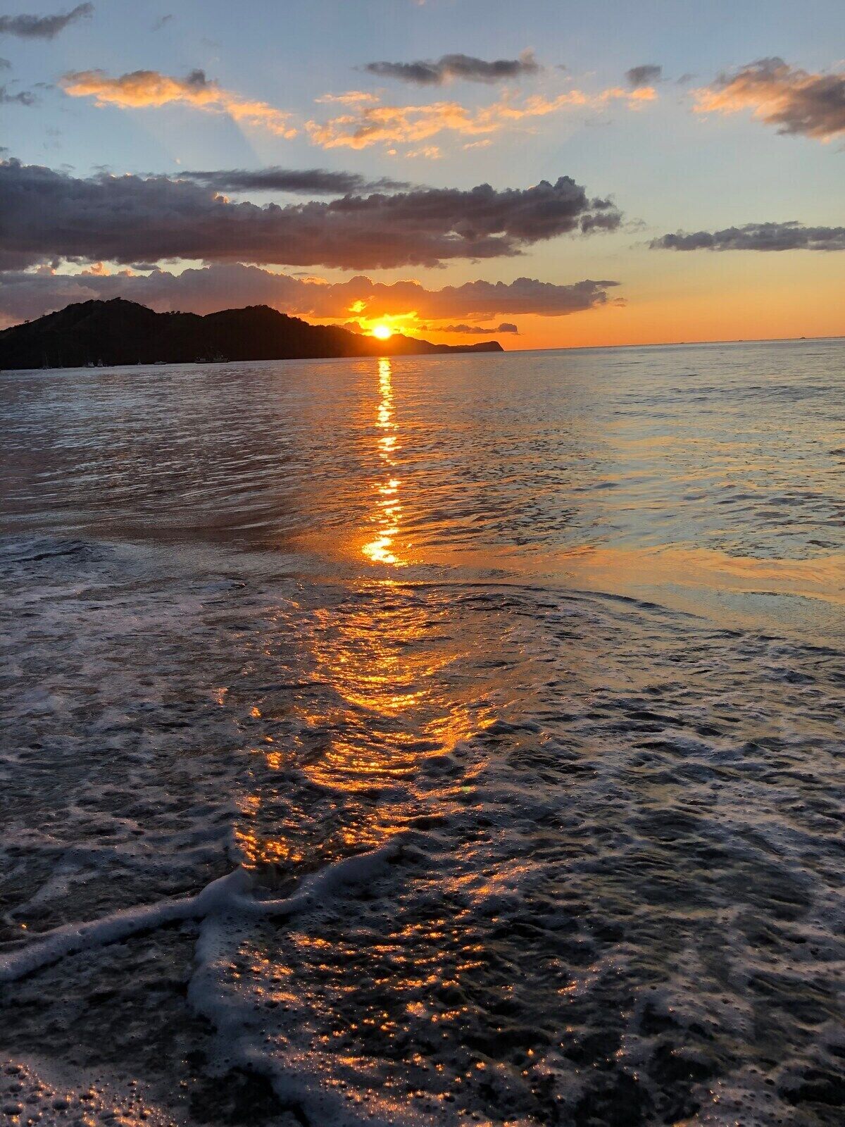 A beach scene with the sun reflecting on the water, creating a path of light.