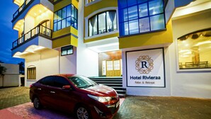 A red car parked in front of Hotel Rivieraa, with a signboard displaying the hotel's name and tagline. - Hotel Rivieraa (Vanur)