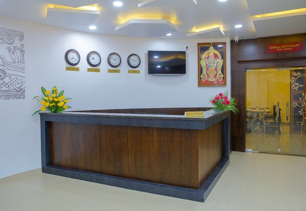 A reception desk with clocks, a TV, and a framed picture on the wall.