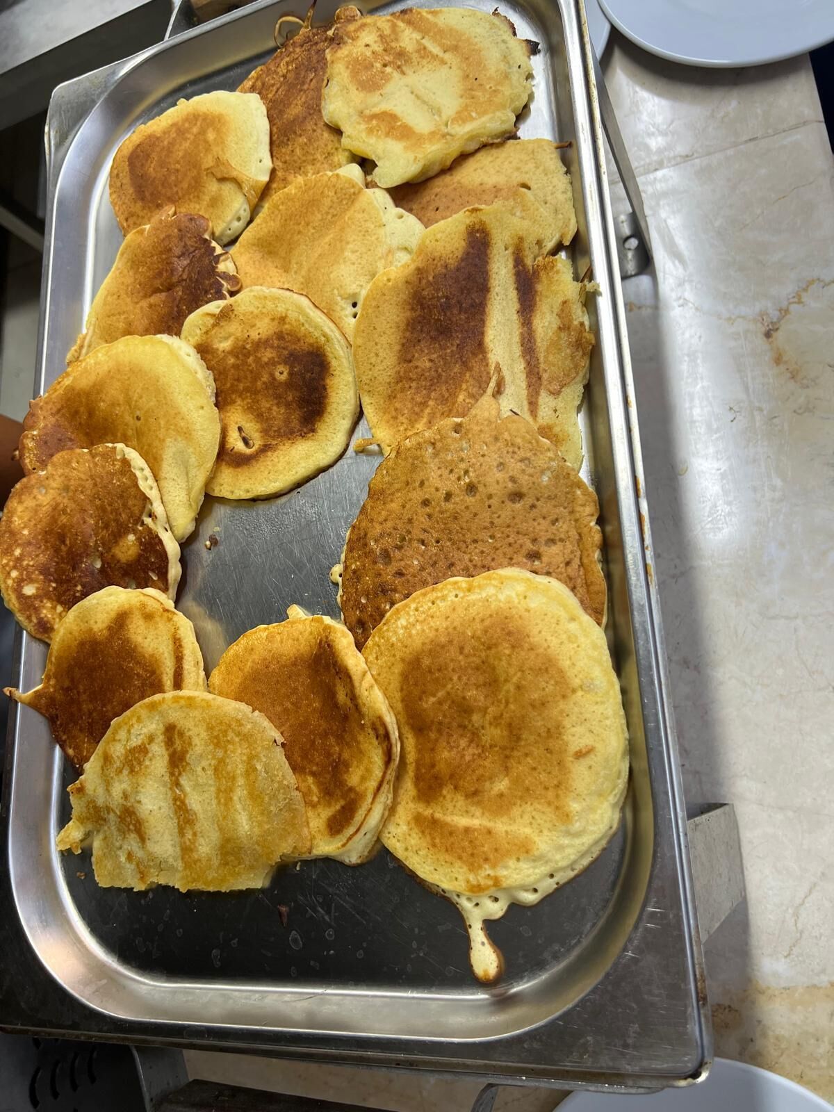 A tray of pancakes on a stainless steel surface.