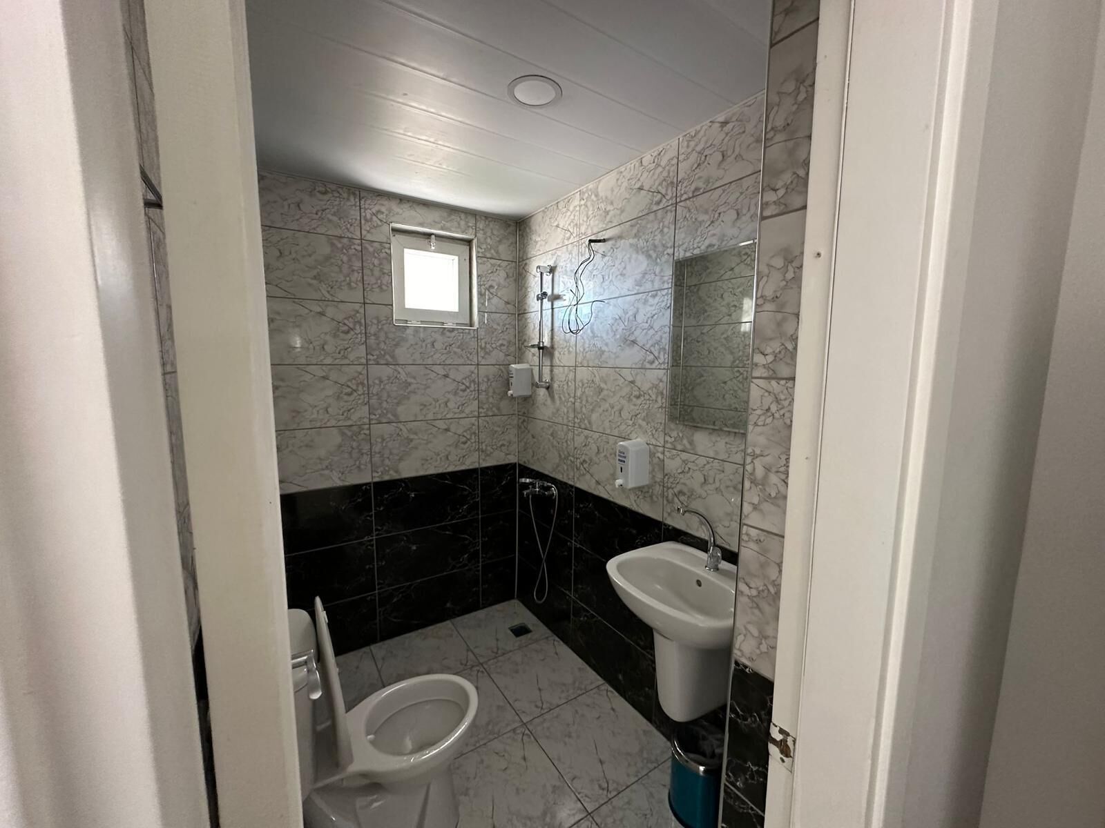 A bathroom with a toilet, bidet, and sink, tiled in marble and black tiles.