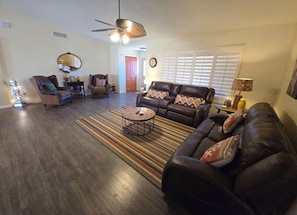 A living room with a dark leather sofa, two armchairs, a coffee table, and a patterned rug.
