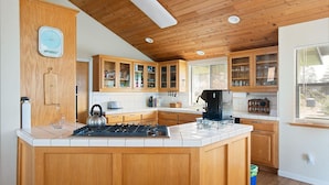 A kitchen with wooden cabinets, a gas stove, a kettle, and a coffee maker.