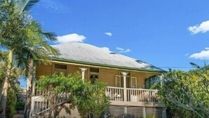 A single-story house with a porch, surrounded by tropical vegetation. - Massinger Hideaway (Byron Shire)