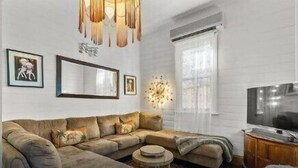 A modern living room with a sectional sofa, a round coffee table, a TV stand, and decorative wall art. - Massinger Hideaway (Byron Shire)