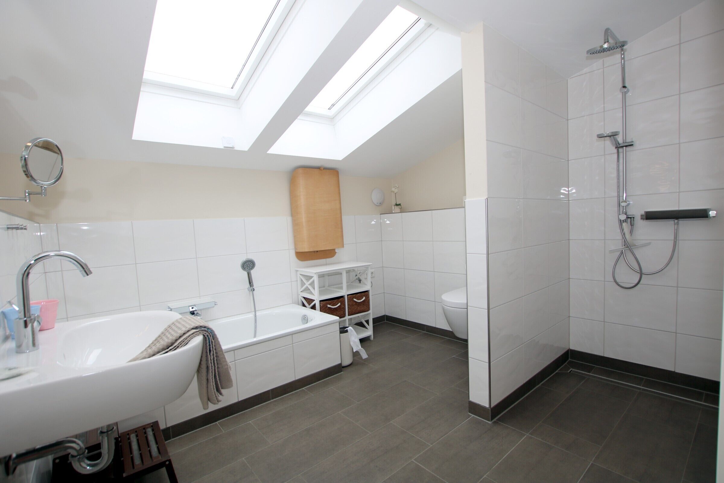 A modern bathroom with skylights, a bathtub, a shower, and a toilet.