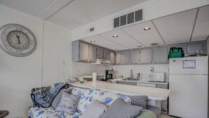 A modern kitchen with white cabinets, a white refrigerator, and a clock on the wall. - 15% off 5 nights or more (Ocean City)