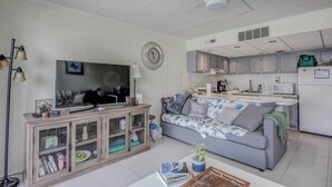 A living room with a television, sofa, and a cabinet with glass doors. - 15% off 5 nights or more (Ocean City)