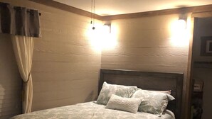 Un dormitorio con cama, ventilador de techo y mesita de noche.