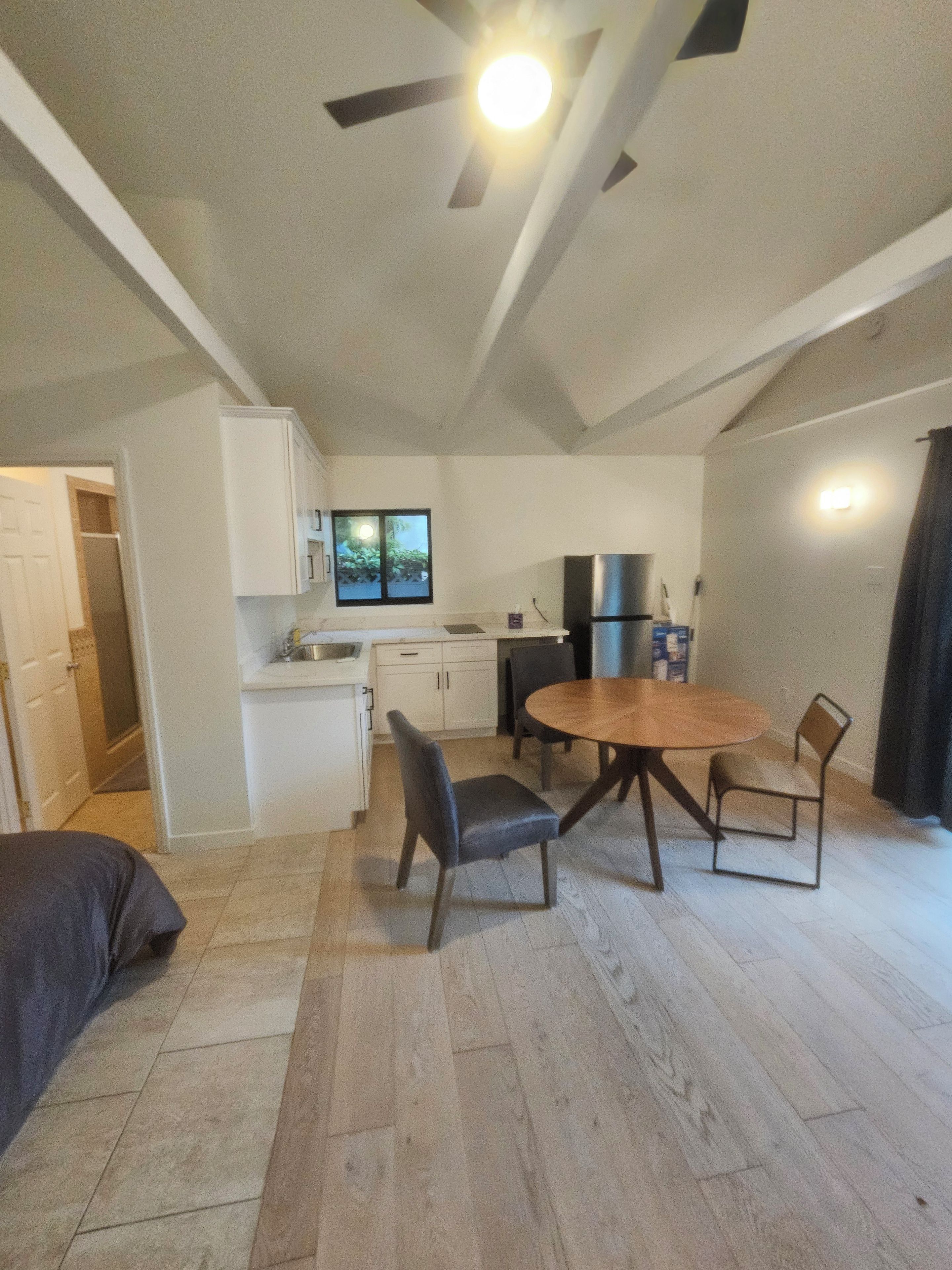 Ett kompakt bostadsutrymme med matplats, litet kök och en takfläkt.
