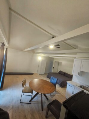 Un espacio habitable moderno con una mesa de comedor, un sofá, una kitchenette y un ventilador de techo.