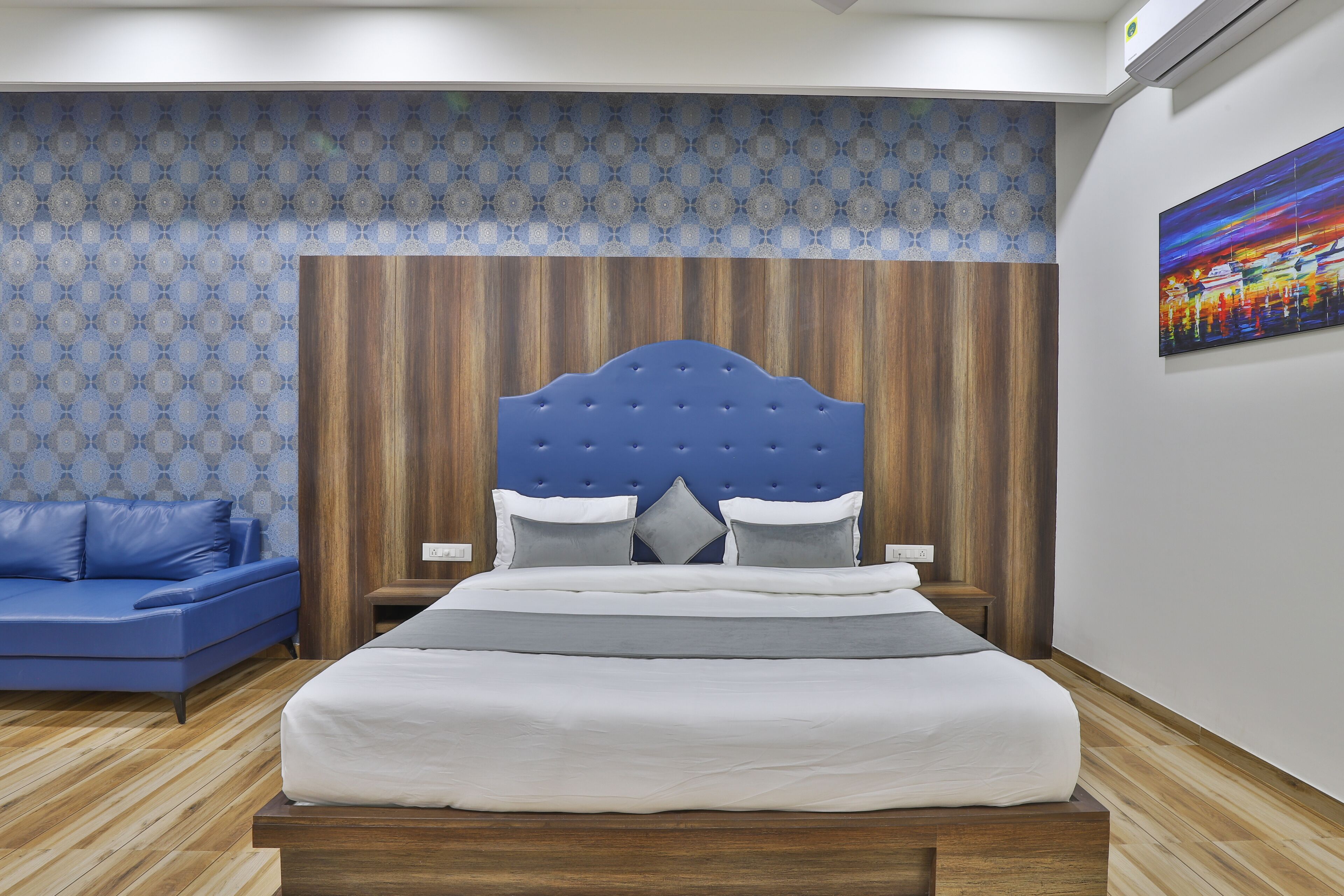 Une chambre à coucher avec un lit, un canapé bleu et un mur recouvert d’un papier peint à motifs.