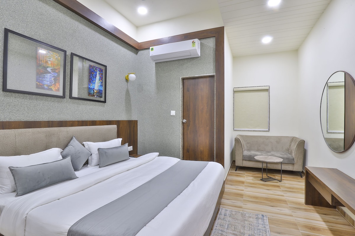 Un dormitorio con cama, sofá, una mesita y un espejo.