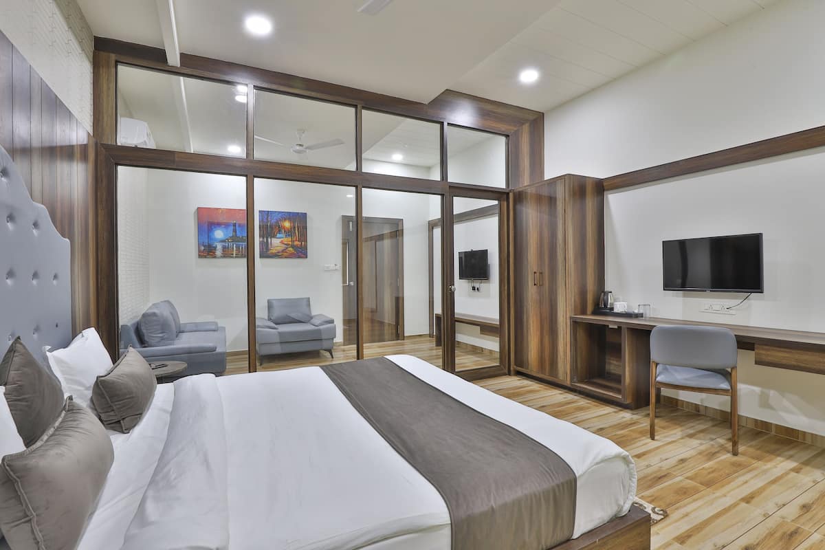 Habitación de hotel con una cama grande, un escritorio, una silla, un televisor y una puerta corrediza de vidrio que da al baño.