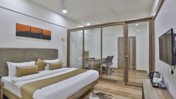 A modern bedroom with a large bed, a glass door leading to a dining area, and a mounted TV.