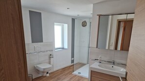Een moderne badkamer met toilet, wastafel en douche.