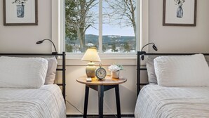 Une chambre avec deux lits, une table de chevet avec une lampe, une horloge et une petite plante en pot.