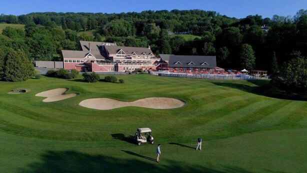 A golf course with a clubhouse, sand bunkers, and a golf cart. - Fireplace Condo, Pet-Friendly, Newton Village (Quechee)