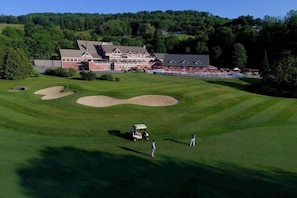 A golf course with a clubhouse, sand bunkers, and a golf cart. - Fireplace Condo, Pet-Friendly, Newton Village (Quechee)