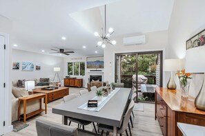 A modern living room with a dining area, a fireplace, and a view of the outdoors.