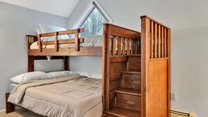 A bunk bed with a wooden ladder, a window with a view of trees, and a carpeted floor. - Fireplace Condo, Pet-Friendly, Newton Village (Quechee)