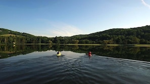 Un lac paisible où l’on peut faire du kayak, entouré de collines boisées.