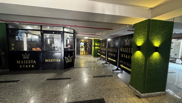 A reception area with black reception desks labeled "MAJESTA STAYS" and directional arrows. - Hotel Leo Saffron (New Delhi)